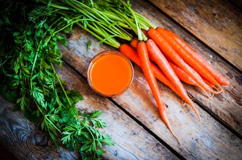 Fresh-squeezed carrot juice on wooden background